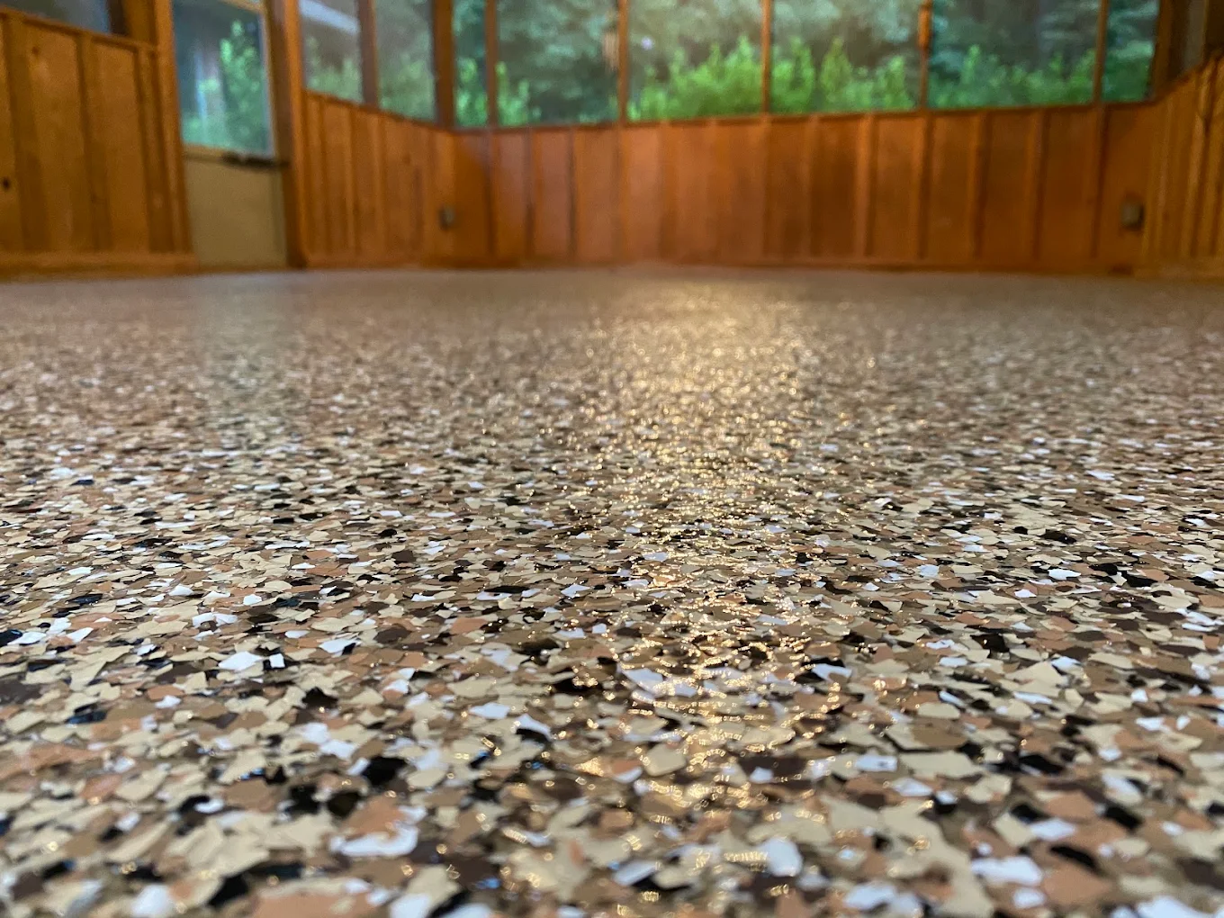 Close-up of a multi-color flake epoxy floor in a wood-paneled room