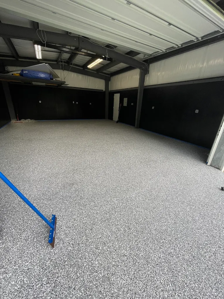 Gray and white flake epoxy floor in a metal-building garage with the edges still taped