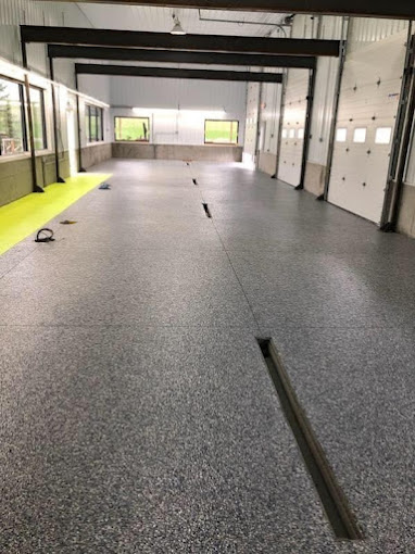 Flake epoxy floor with a trench drain running through a long multi-bay shop