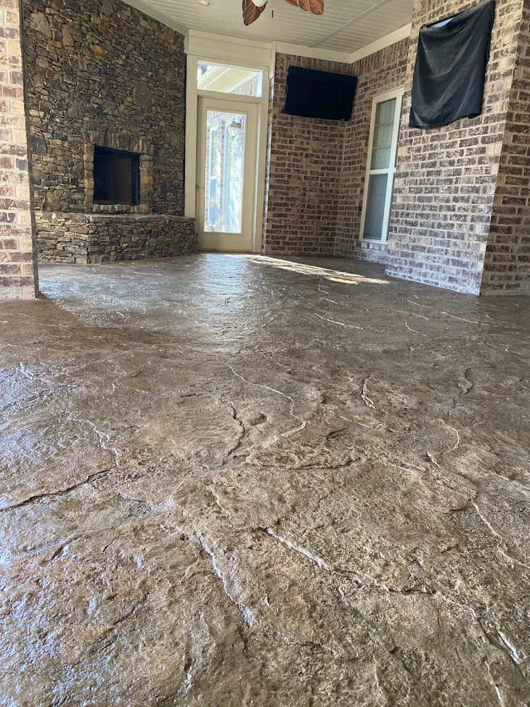 Stamped stone-pattern concrete floor on a covered patio with a stone fireplace